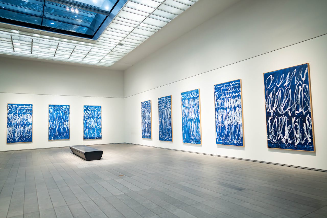 Spacious modern art gallery featuring a collection of blue abstract paintings on display.