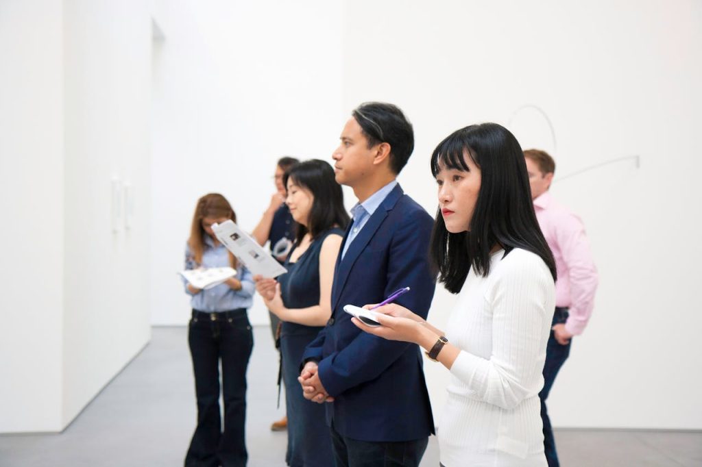 A group of people attentively viewing art installations in a modern gallery setting.